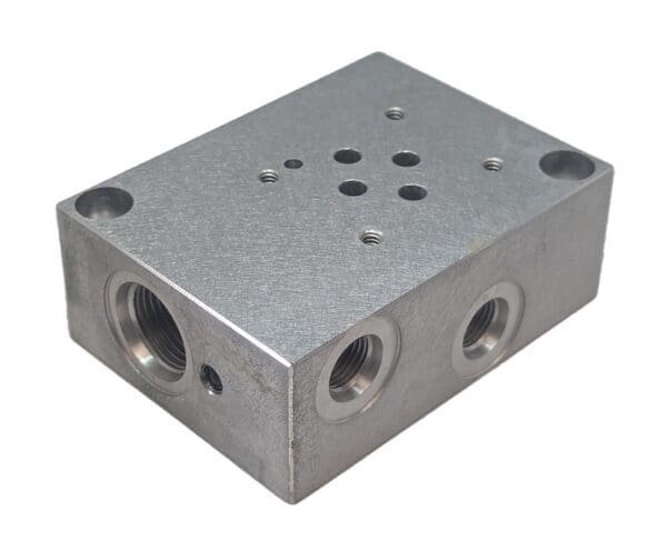 A metal block with four holes and three different valves.