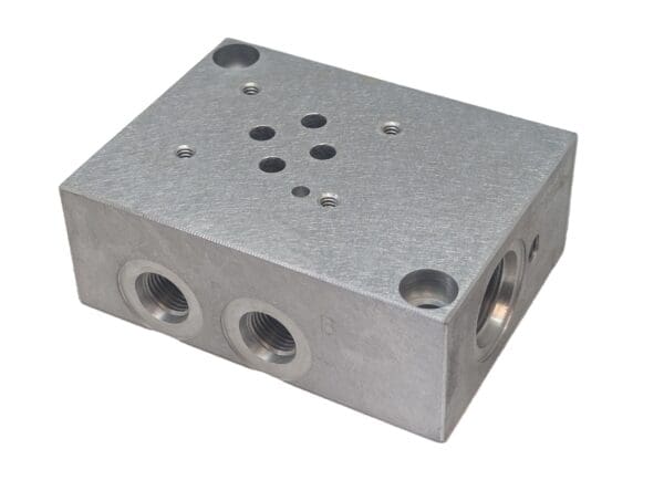 A silver block with holes for valves and three different locations.